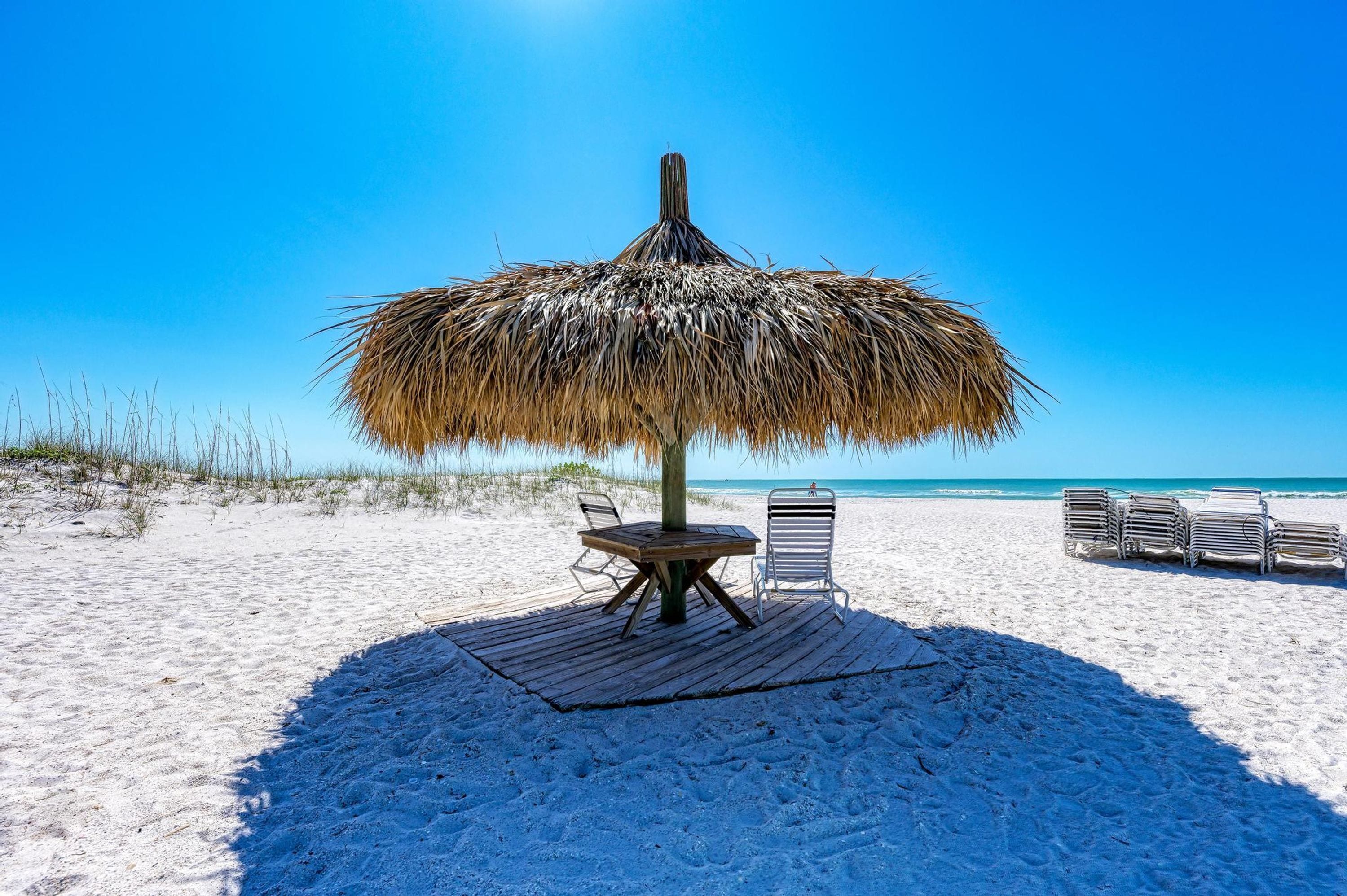 Un parasol de plage avec une table et des chaises, installé sur une plage de sable.