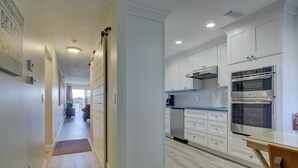 A modern kitchen with white cabinets, a stainless steel oven, and a blue countertop. - Anna Maria Island Beach Palms 5B (Bradenton Beach)