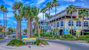 A street corner with a sign for Historic Bridge Street, surrounded by palm trees and buildings with balconies. - Anna Maria Island Beach Palms 5B (Bradenton Beach)