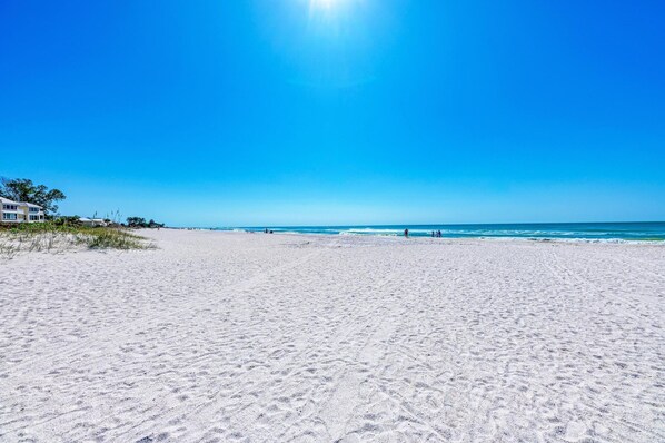 Ein weiter Sandstrand mit blauem Himmel und Meer.