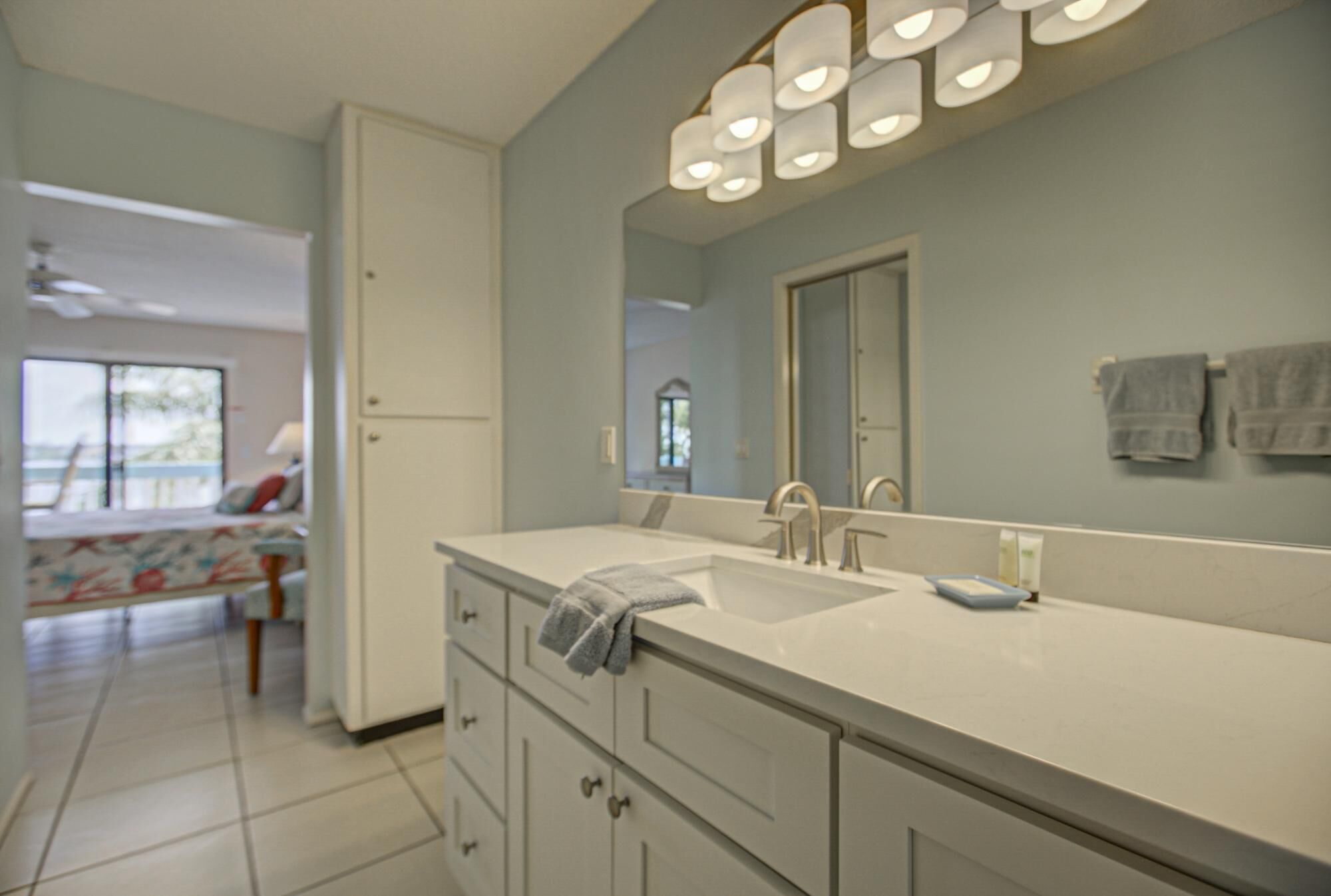 A bathroom with a large mirror, a sink, and a towel rack.