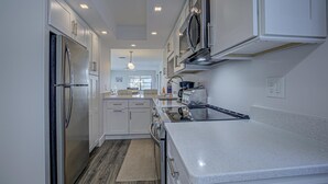 Une cuisine moderne avec des meubles blancs, des appareils en acier inoxydable et un îlot central.