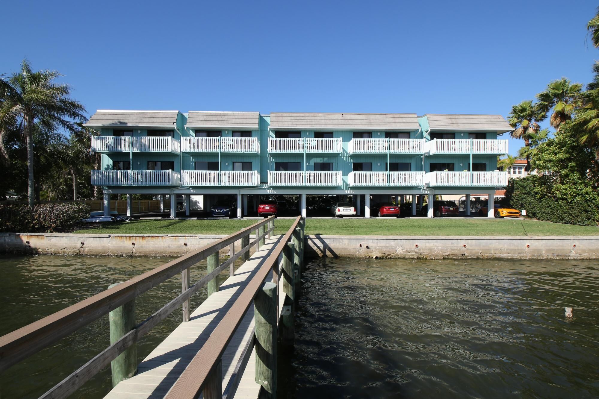 A multi-story hotel with a waterfront view, featuring balconies and a dock extending into the water.