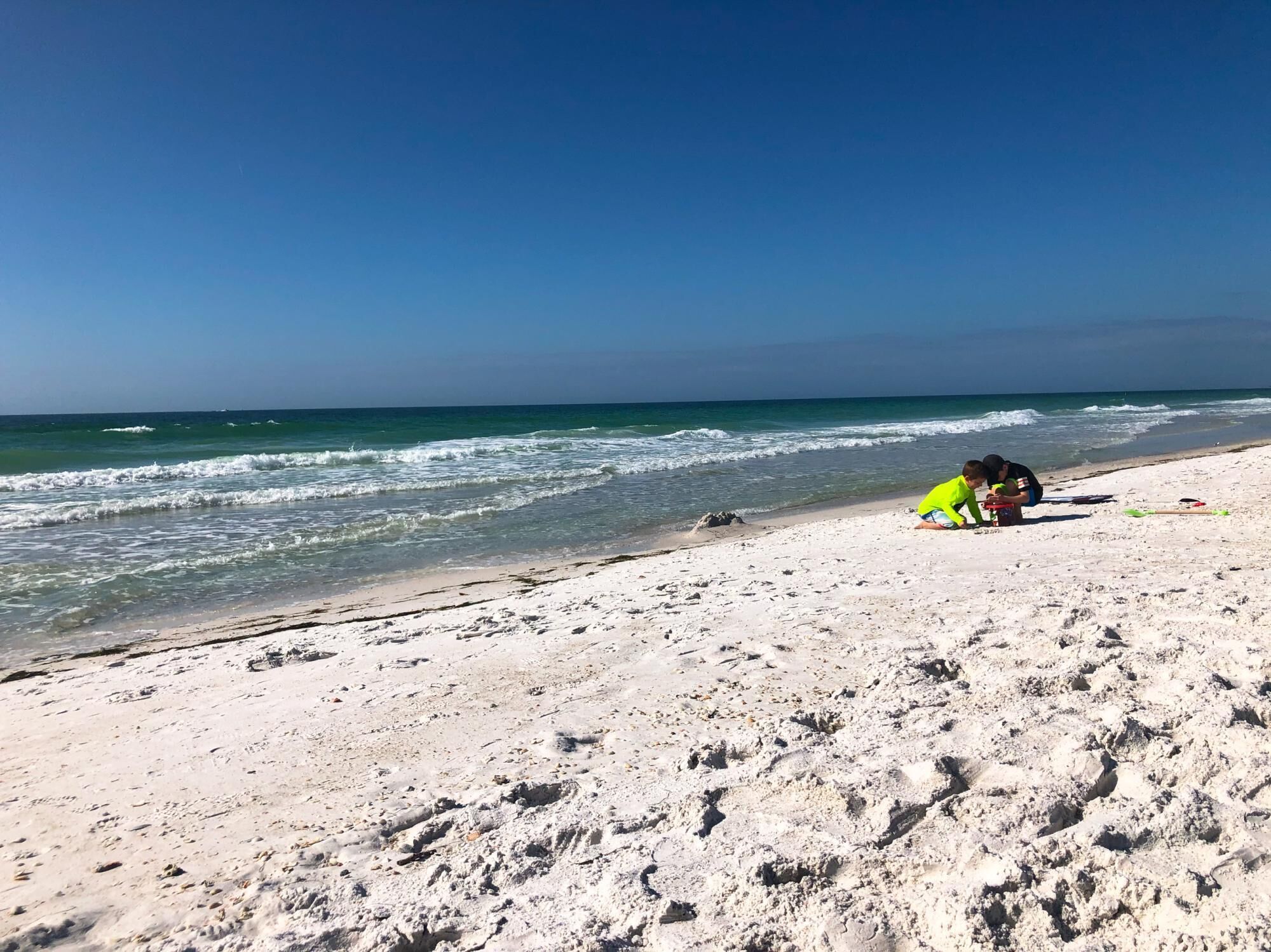 Una playa arenosa con huellas que se adentran en el agua.