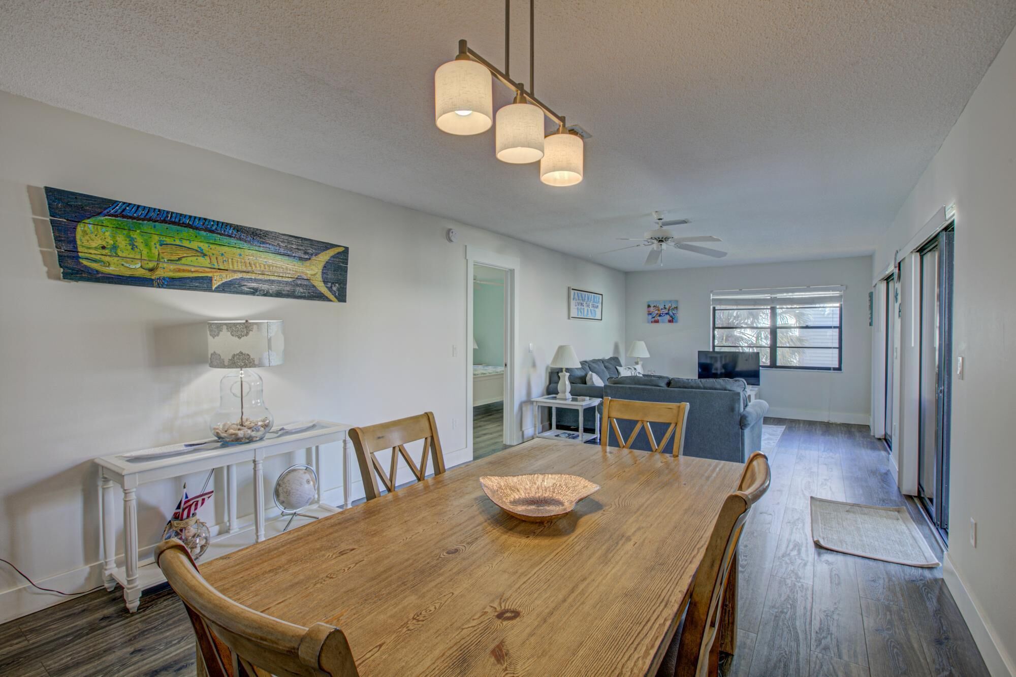 A dining area with a wooden table, chairs, and a hanging light fixture.