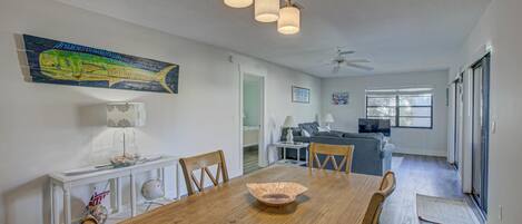 A dining area with a wooden table, chairs, and a hanging light fixture.