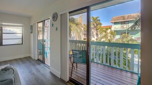 Une pièce dotée d’une porte-fenêtre coulissante donnant sur un balcon avec vue sur des palmiers et un immeuble.