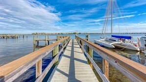 A wooden pier leading to a dock with boats moored at the end.