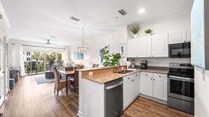 A modern kitchen with white cabinetry, stainless steel appliances, and a central island. - Modern 2br/2ba, Pet friendly, steps to private beach access and restaurants! (Miramar Beach)