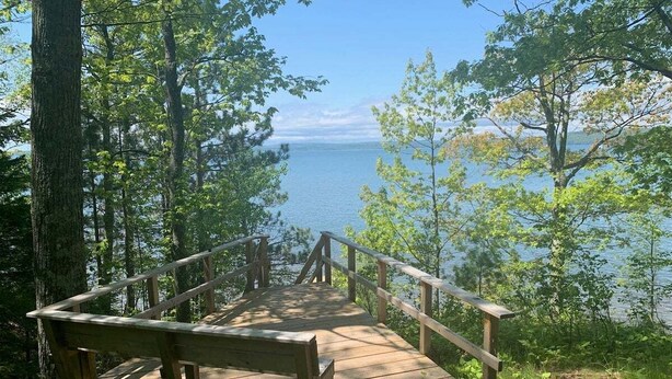 Une terrasse en bois avec un banc donnant sur un lac.