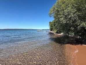 Una spiaggia limpida con acque calme, un litorale roccioso e una fitta vegetazione.