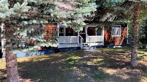 A cabin with a porch, surrounded by trees.