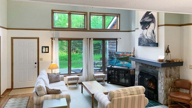 Una sala de estar con chimenea, televisor y vistas al exterior.