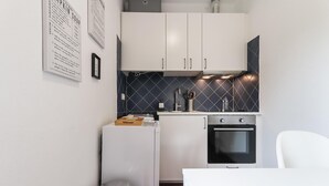 A compact kitchen with white cabinets, a black oven, and a tiled backsplash. - Belem Boutique IV by Homing (Lisbon)