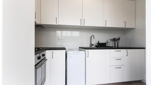 A kitchen with white cabinets, a black countertop, and a built-in refrigerator. - Belem Boutique VI by Homing (Lisbon)
