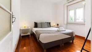 A bedroom with a bed, bedside tables, a window, and an air conditioning unit. - Belem Boutique IX by Homing (Lisbon)