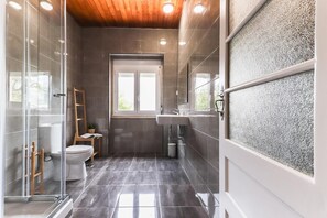 A modern bathroom with a glass shower enclosure, a white sink, and a window providing natural light. - Belem Boutique IX by Homing (Lisbon)