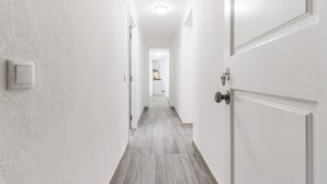 A hallway with white walls and a wooden floor leading to a kitchen area. - Belem Boutique II by Homing (Lisbon)