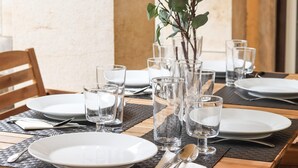 A dining table set with plates, glasses, and cutlery, accompanied by a vase with green foliage. - Belem Boutique II by Homing (Lisbon)