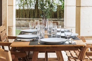 A wooden dining table set with plates, cutlery, and clear glasses, surrounded by wooden chairs. - Belem Boutique II by Homing (Lisbon)