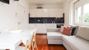 A modern kitchen with white cabinets, a black backsplash, and a dining area with a white table and chairs. - Belem Boutique Viii by Homing (Lisbon)