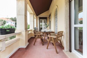A covered outdoor dining area with a table and chairs, a potted plant, and a view of the street. - Belem Boutique V by Homing (Lisbon)