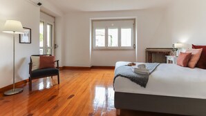 A bedroom with a bed, a chair, a lamp, a window, and a small table. - Belem Boutique V by Homing (Lisbon)