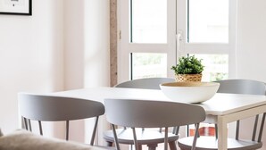 A dining area with a white table and grey chairs, a woven basket with a plant, and a framed picture on the wall. - Belem Boutique V by Homing (Lisbon)