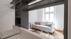 A modern living room with a white sofa, a glass coffee table, and a window with natural light. - Italianway Easy - Sarpi 10 A (Milan)