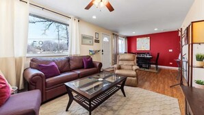 A living room with a glass coffee table, leather sofa, and a red accent wall. - PROMO 15% MONTHLY DISCOUNT!
Cozy House, Close to Benedictine & North Central (Lisle)