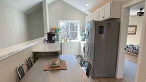 Una cocina moderna con una isla central, armarios blancos y un refrigerador empotrado.
