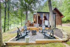 A cabin with a deck, outdoor seating, and a fire pit.