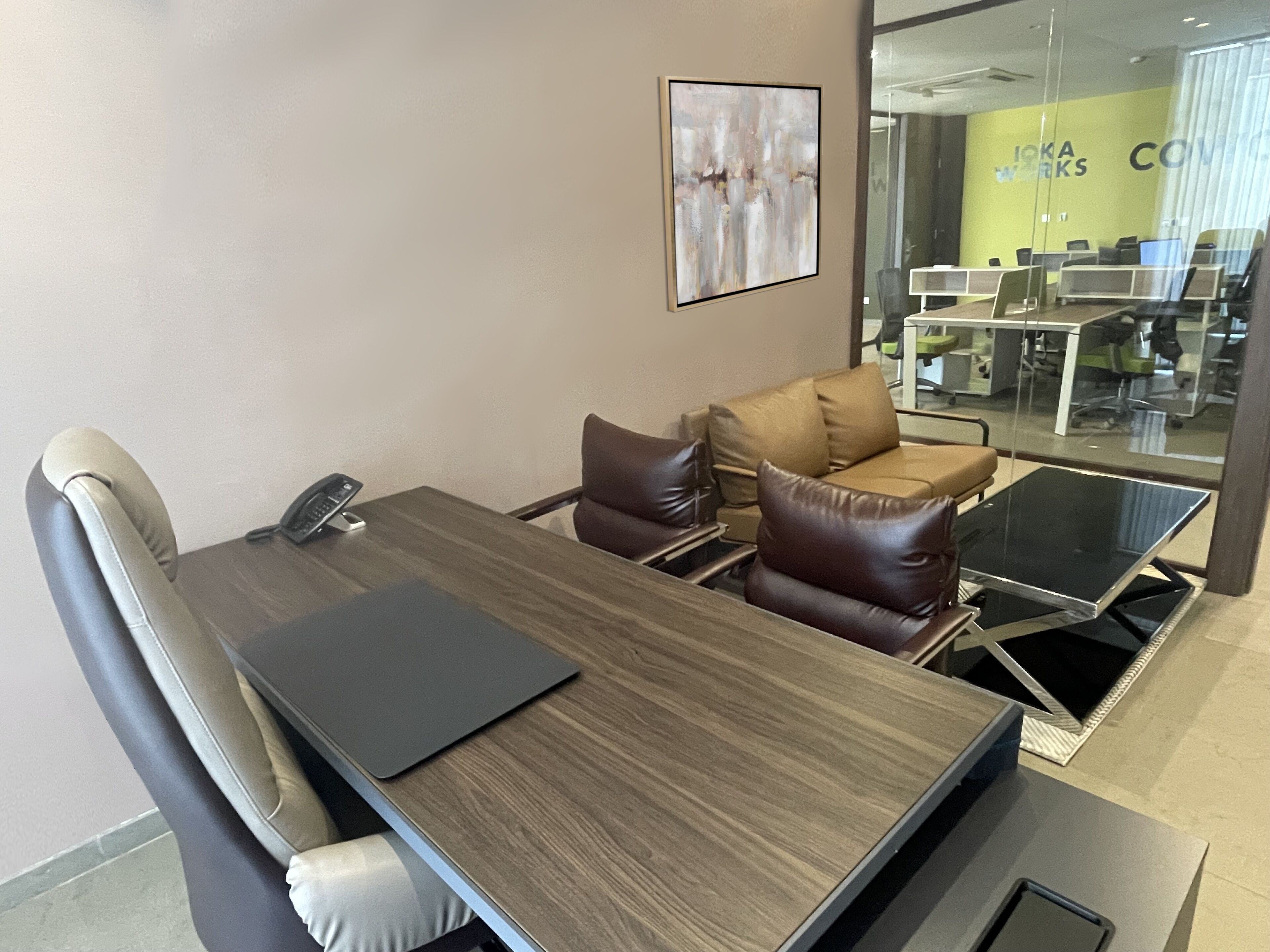 A conference room with a wooden table, leather chairs, and a laptop.