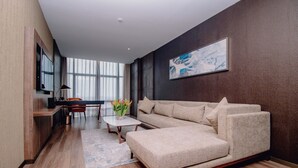 A modern living room with a sofa, coffee table, and a dining area with a table and chairs. - CIKA Golden Hotel and Suites (Lomé)