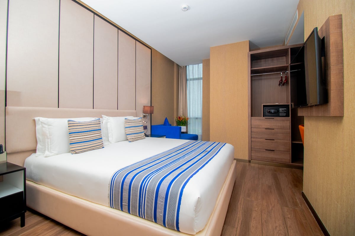Quarto de hotel com uma cama grande, televisão na parede e um guarda-roupa.