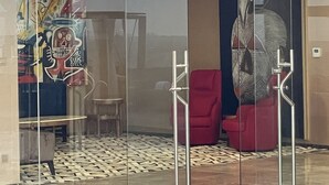 A modern lobby with a glass partition, a red chair, a wooden floor, and a tiled area. - CIKA Golden Hotel and Suites (Lomé)