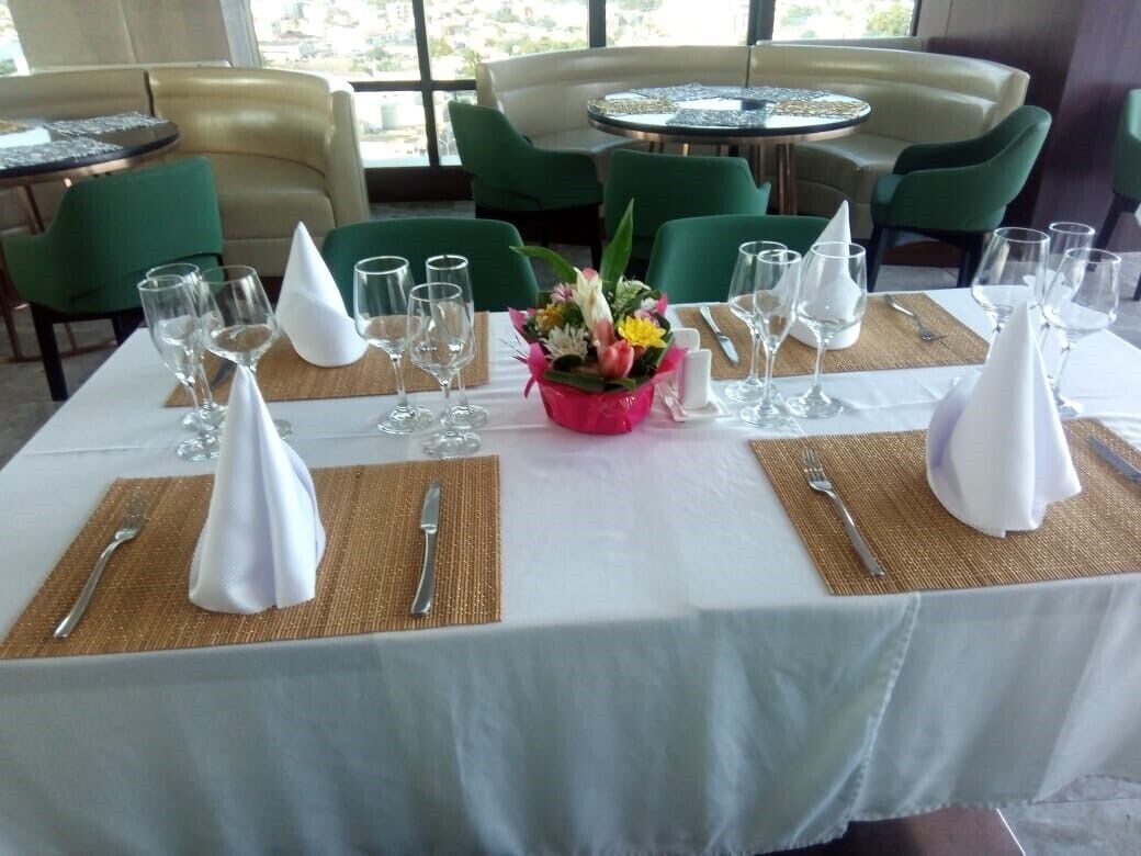 A dining table set with white tablecloth, gold placemats, and a centerpiece of flowers.