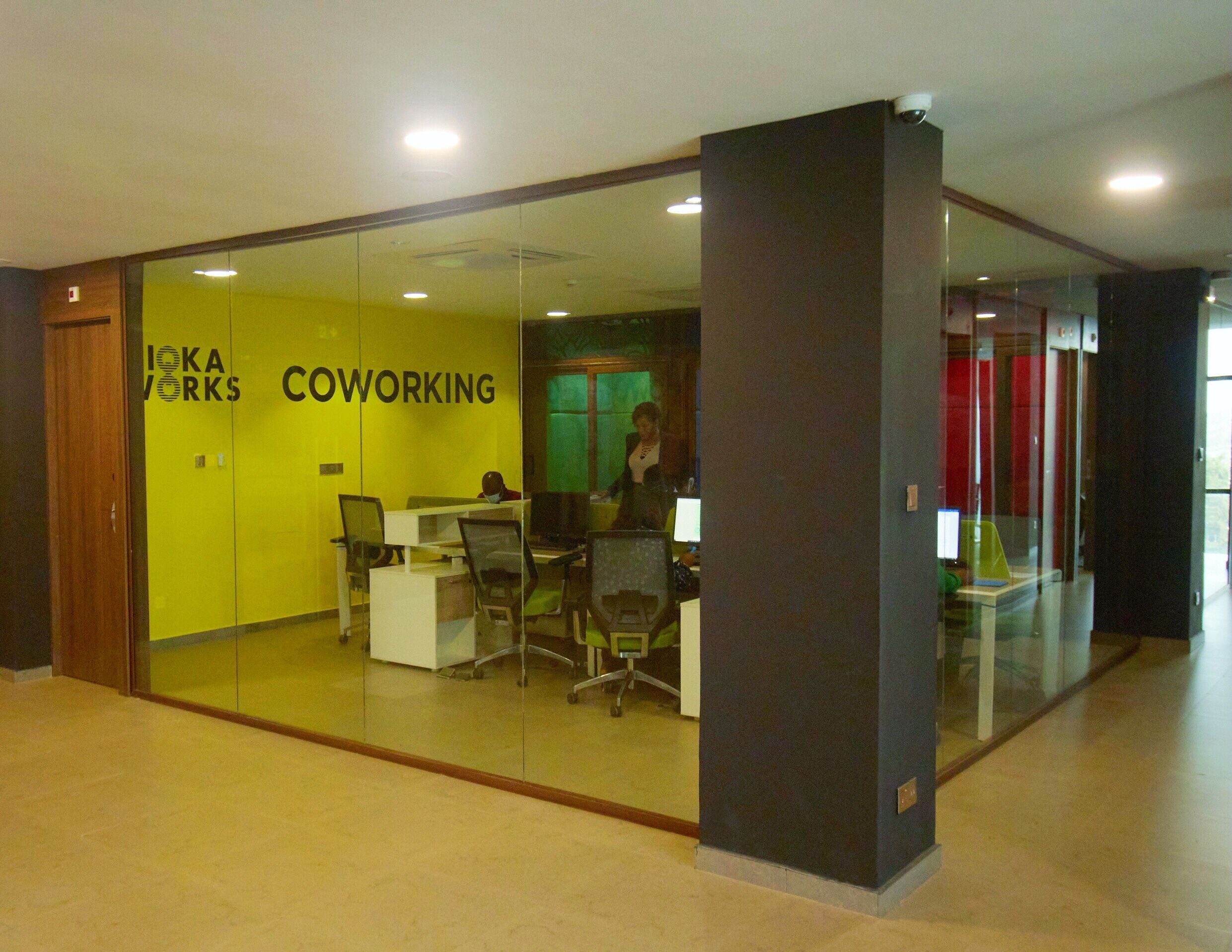 Een kantoorruimte met glazen wanden, met een bord waarop staat: 'IKEA WORKS COOWORKING'.