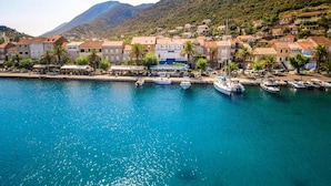 A coastal town with a marina, buildings with red-tiled roofs, and a mountainous backdrop. - Guesthouse Aurora - Double Room with Sea View - 3 (Trpanj)
