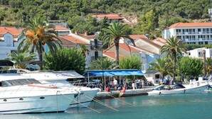 Un puerto deportivo con barcos amarrados, un paseo marítimo y edificios con tejados rojos.