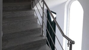 Un escalier avec des rampes en métal et un luminaire fixé au mur.