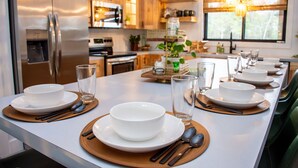 A modern kitchen with stainless steel appliances, wooden cabinets, and a dining area set for a meal.