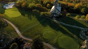 A golf course with a church and a lake in the background.