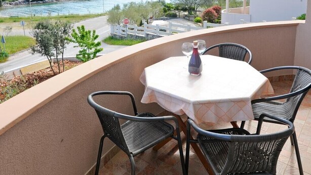 Een balkon met een tafel en stoelen, met uitzicht op een rivier en groen.