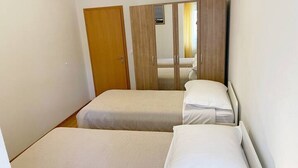 Een kamer met twee bedden, een kledingkast en een spiegel.