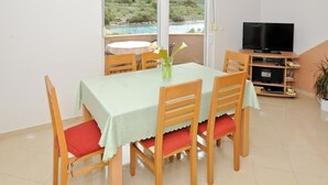 Een eetgedeelte met een tafel, stoelen, een televisie en uitzicht op een natuurlandschap.