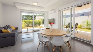 A modern living room with a grey sofa, white chairs, a wooden dining table, and a TV. - Villa Frida - Apartment Fran with Terrace (Premantura)