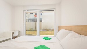 A hotel room with a bed, a desk, and a sliding glass door leading to an outdoor area. - Villa Frida - Apartment Fran with Terrace (Premantura)