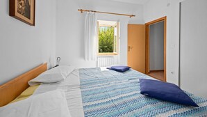Une chambre à coucher avec un lit, une fenêtre avec des rideaux, une porte et un tableau accroché au mur.