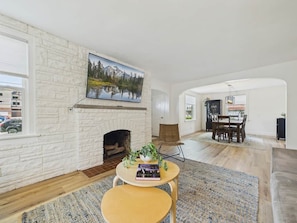 A living room with a fireplace, a dining area, and a view of a mountain landscape.